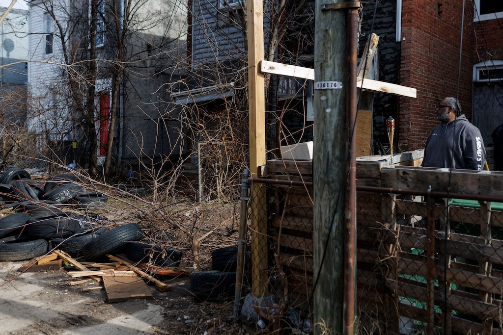 Carlos Harris looks at the debris dumped in the vacant property next door to his family home. The Harris’ family home of generations was sold in a tax sale without the family’s knowledge.