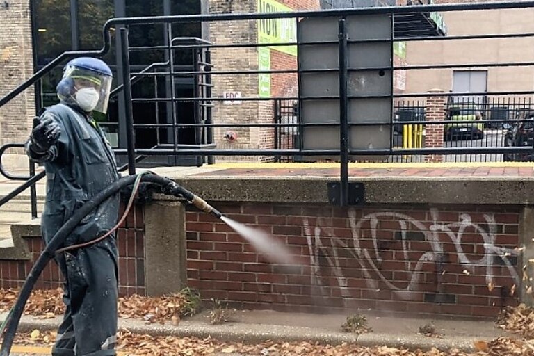 Eric Ford uses a Dustless Blaster to remove spray paint from a Light Rail stop on Howard Street.