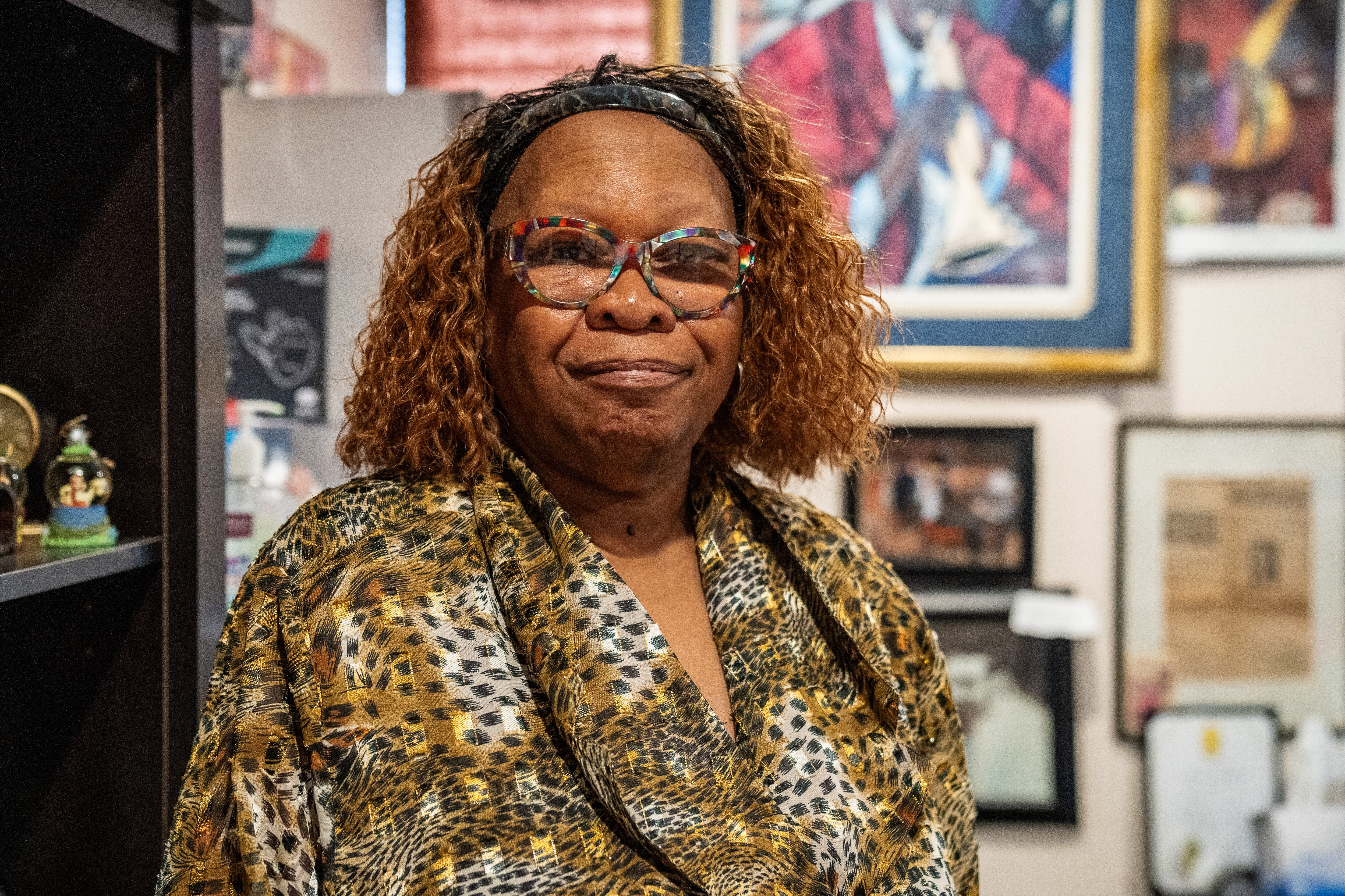 Edna Manns-Lake poses for a portrait in front of framed photos in her office.