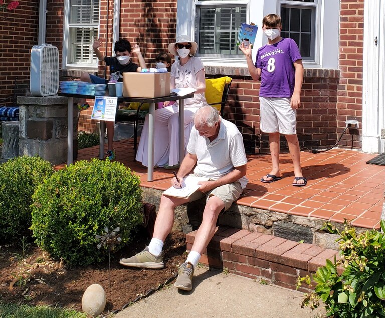 Maryland children’s author Kevin O’Malley signs a book at the Rodgers Forge event celebrating the release of “Super Caveman,” written by 8-year-old local Orion Filippazzo.