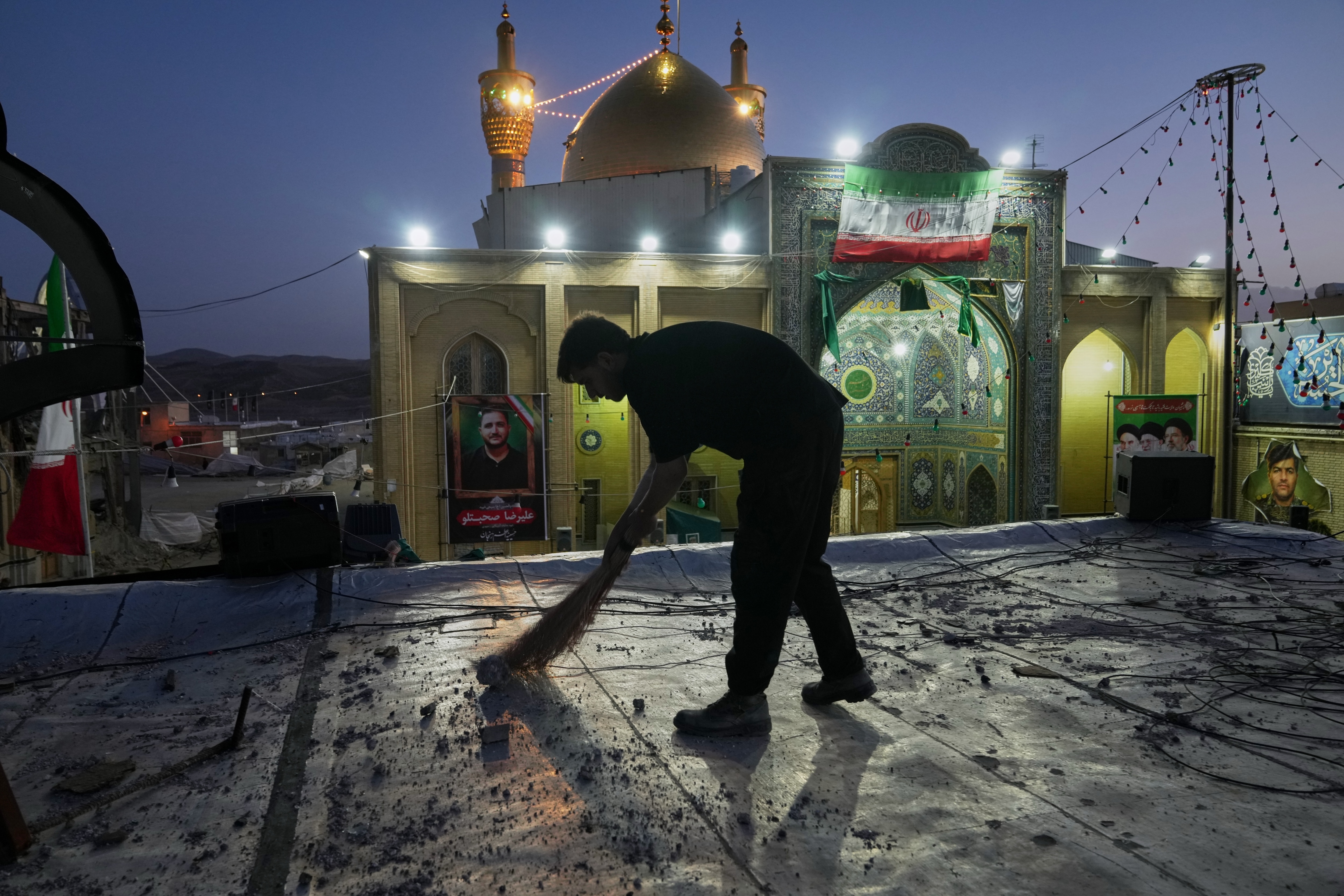 A worker cleans an area within the Grand Hosseiniyeh complex, with the mosque visible in the background, that officials say was hit by U.S.-Israeli airstrikes Tuesday in Zanjan, Iran, Saturday, April 4, 2026.
