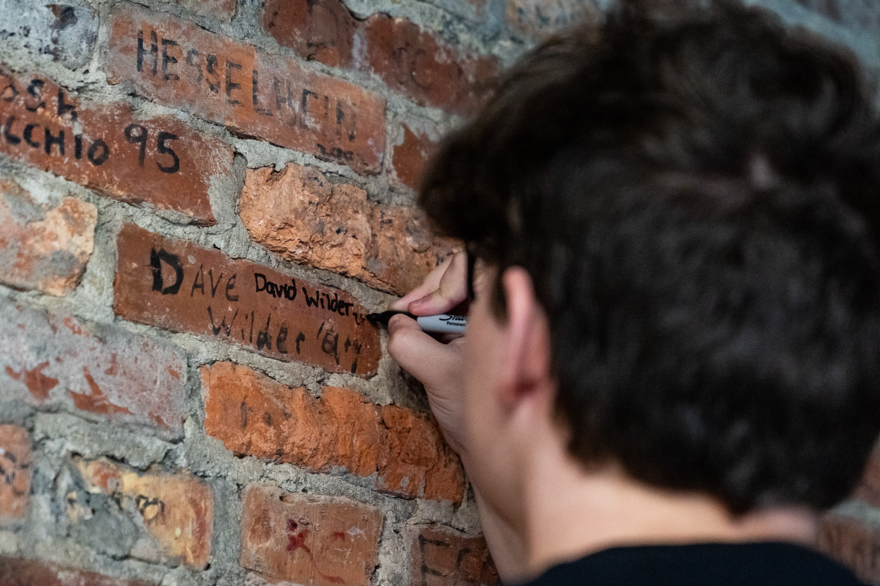 David Wilder signs his name on the same brick his dad, Dave Wilder, signed in 1997 as part of Mount Saint Joseph High School’s graduation rite on May 1, 2024.