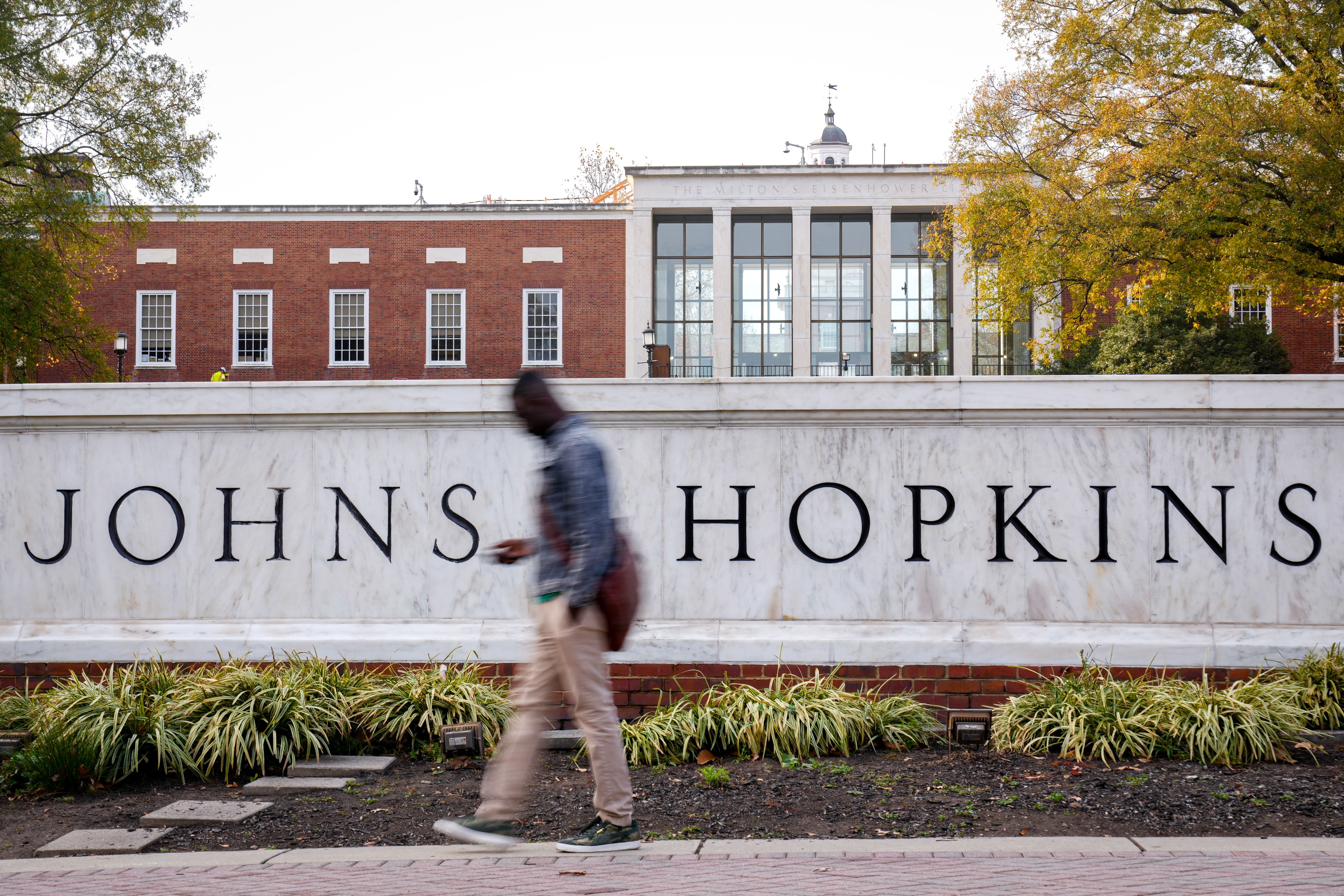 A student passes in front of the Johns Hopkins University sign welcoming people to the Homewood Campus from Charles Street in Baltimore, Md. on Wednesday, November 20, 2024.