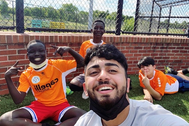 Warshan Hussin (center) takes a selfie with three players on the team he coached.