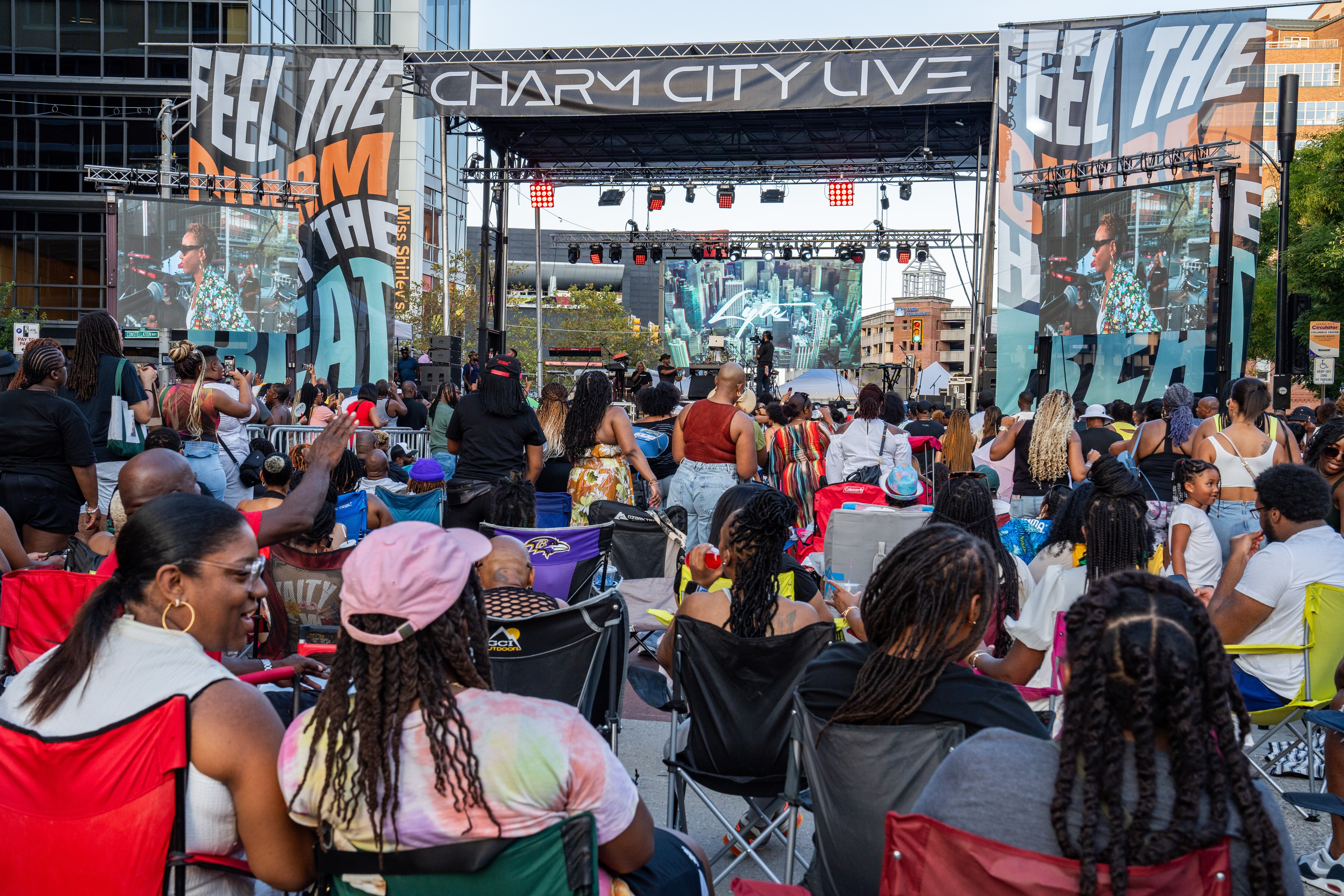 People in lawn chairs listen to MC Lyte’s set in the foreground as people in the background closer to the stage stand.