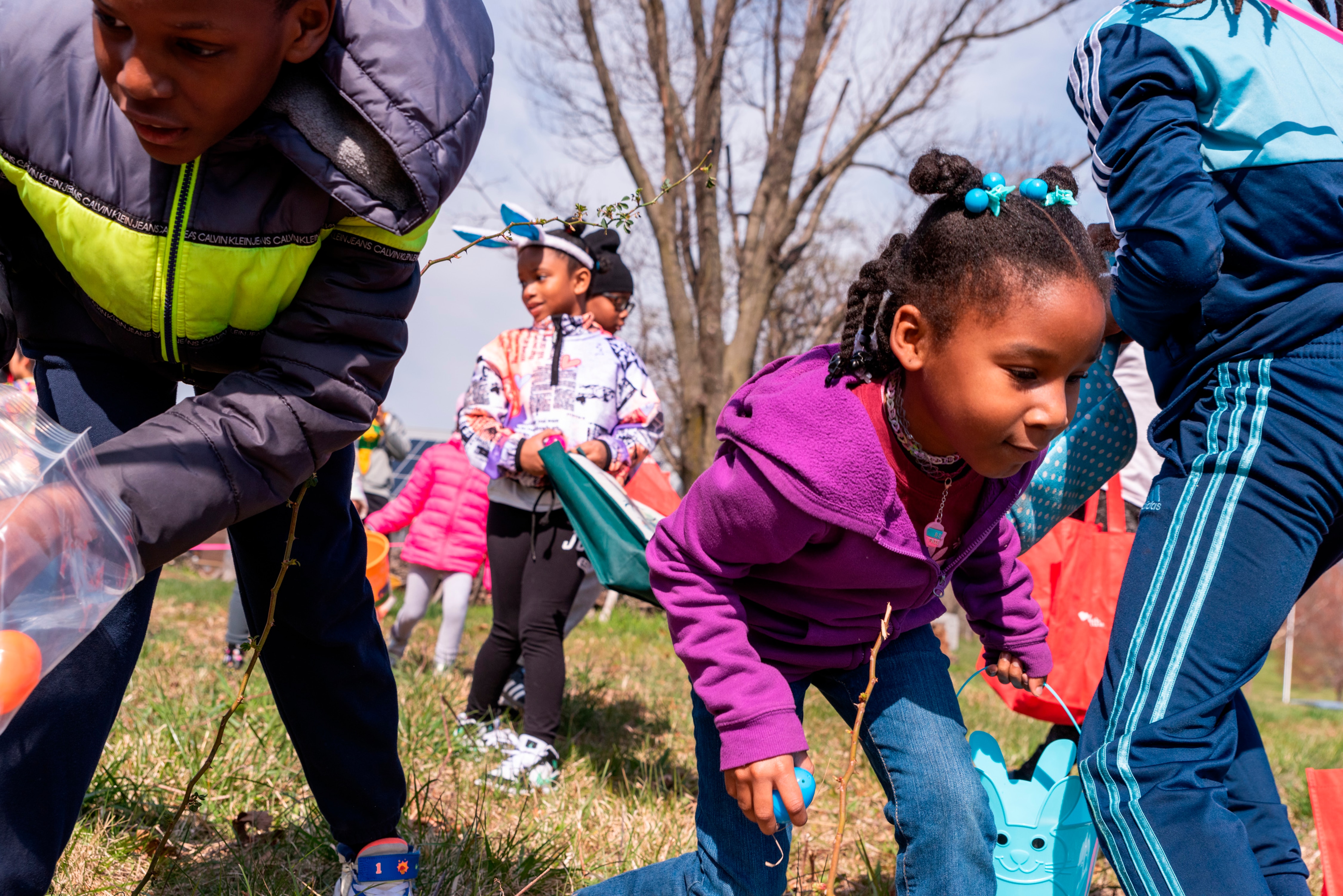 Tristian Figaro, 10, left, and Nahari Bell, 8, pick up up eggs during the egg hunt. Parks & People Easter Egg Hunt, Mar 30 2024, Baltimore, MD.