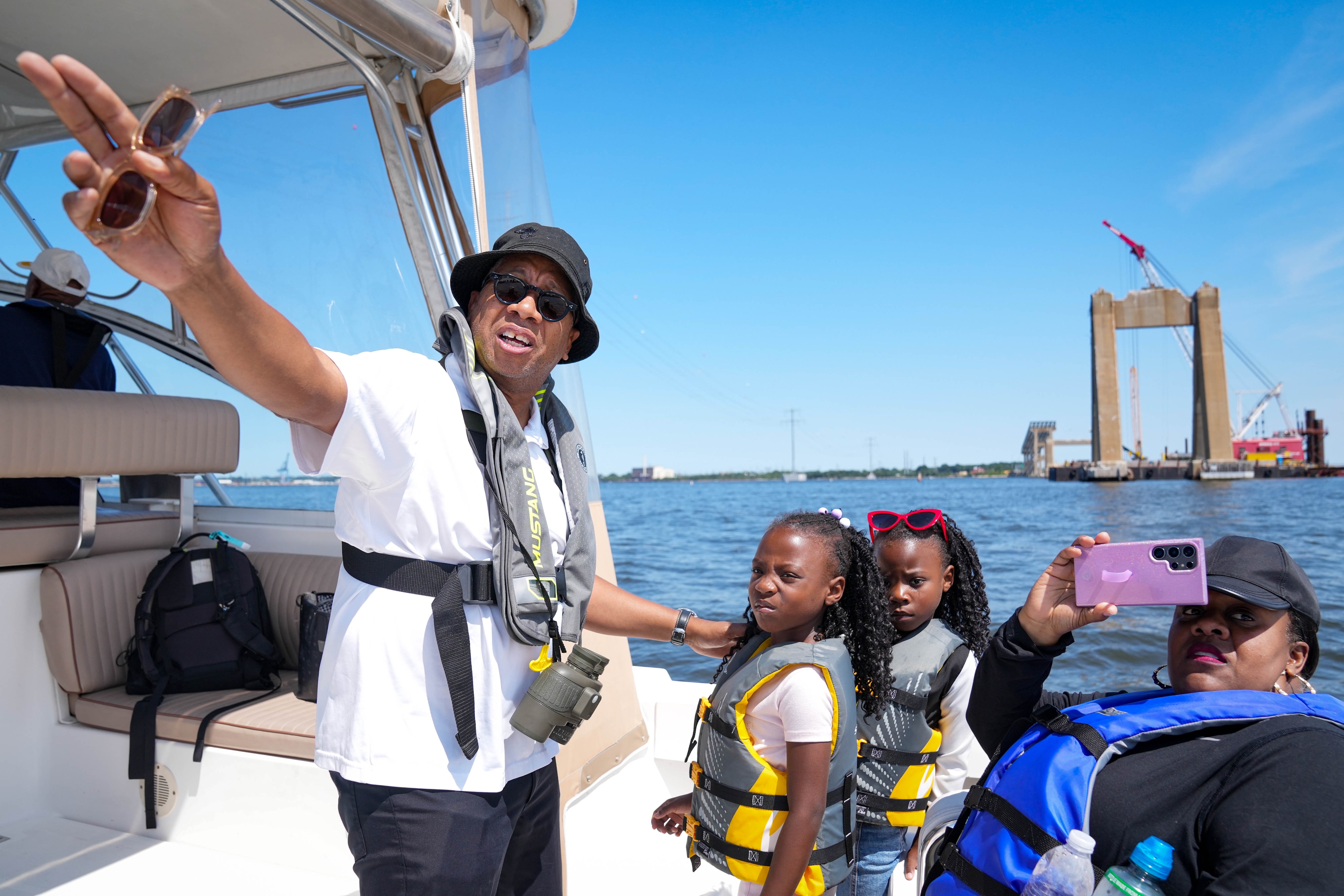 Captain Lafon Porter, left, shares his knowledge of the Francis Scott Key Bridge with 7-year-old twins Kira and Kina Brooks, and their mother, Cheryl Brooks, as they head toward the bridge’s rebuild site.