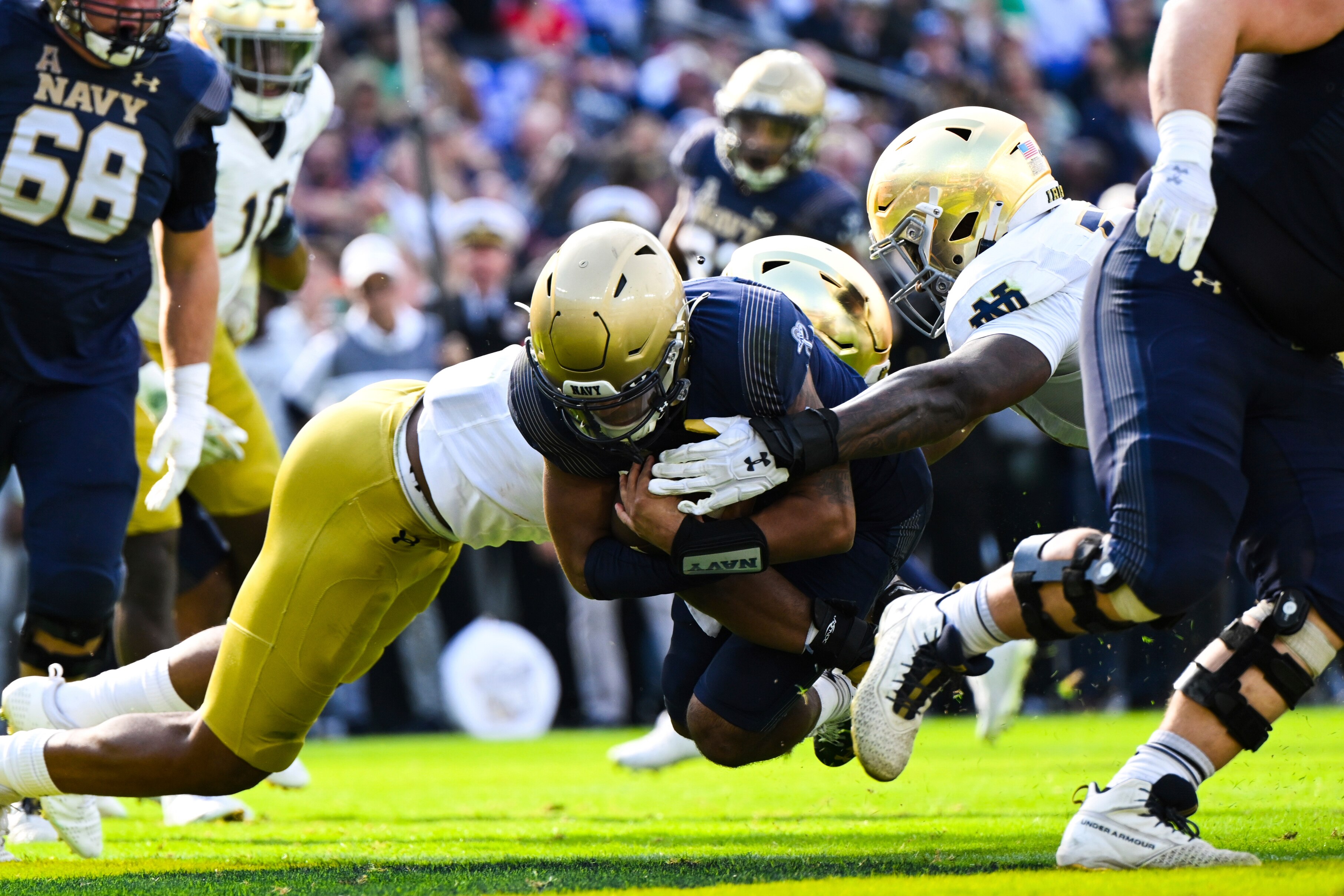Navy quarterback Xavier Arline (7) runs the ball and dives into the end zone for a touchdown against two Notre Dame defenders during the first half of an NCAA college football game, Saturday, Nov. 12, 2022, in Baltimore.