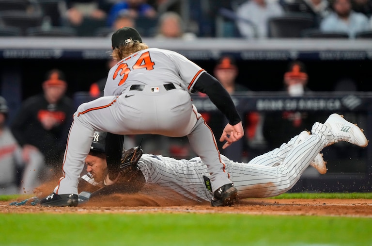 New York Yankees designated hitter Jasson Domínguez, bottom, successfully slides into home to score on a wild pitch by Orioles starting pitcher Shane Baz during the sixth inning.