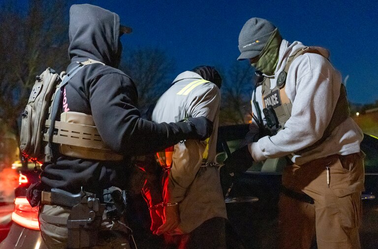 U.S. Immigration and Customs Enforcement officers use a chain to more comfortably restrain a detained person using handcuffs positioned in front, Monday, Jan. 27, 2025, in Silver Spring, Md.