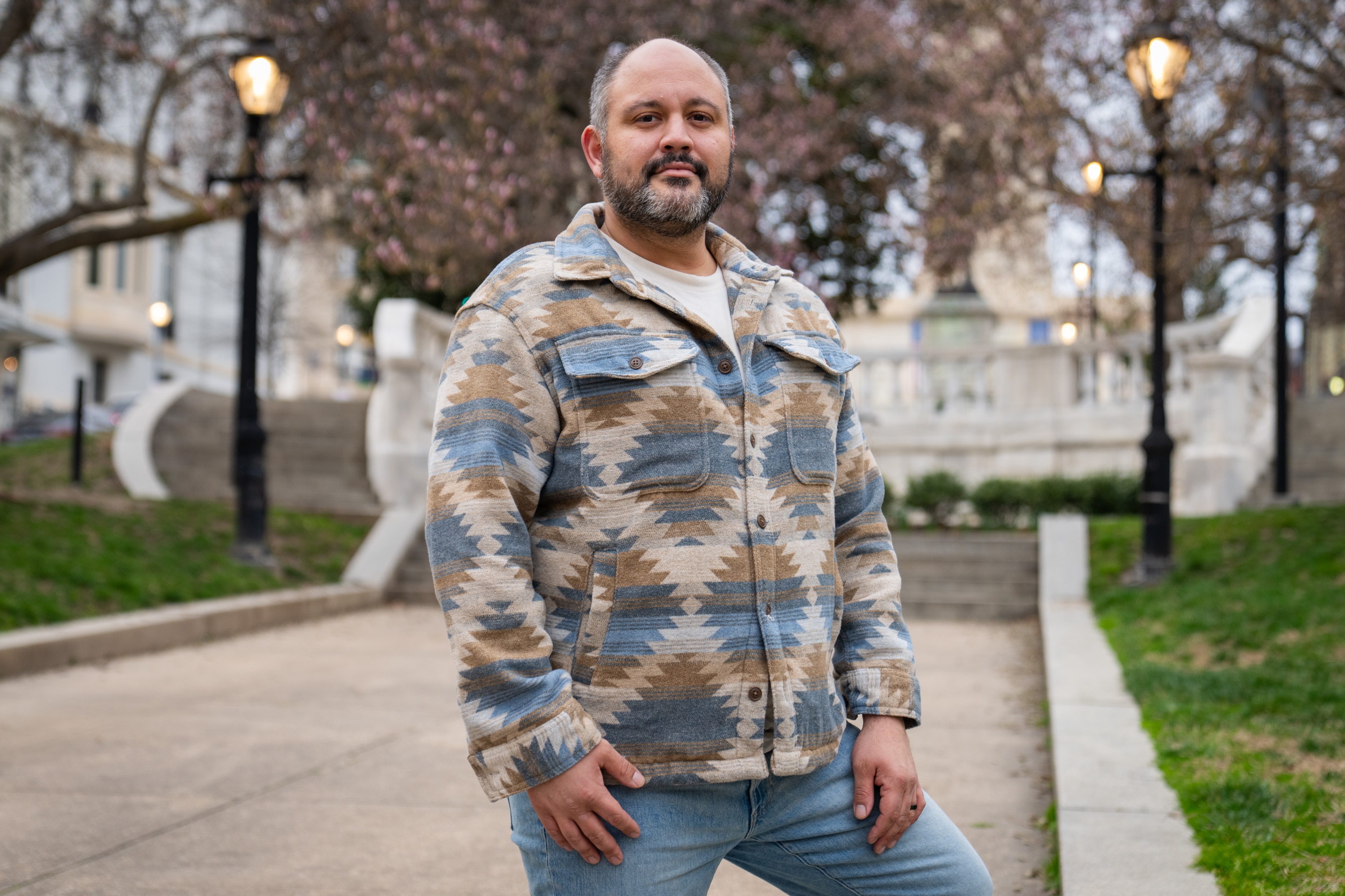Derek Chavis smiles for a portrait in front of blossoming trees at the Washington Monument.