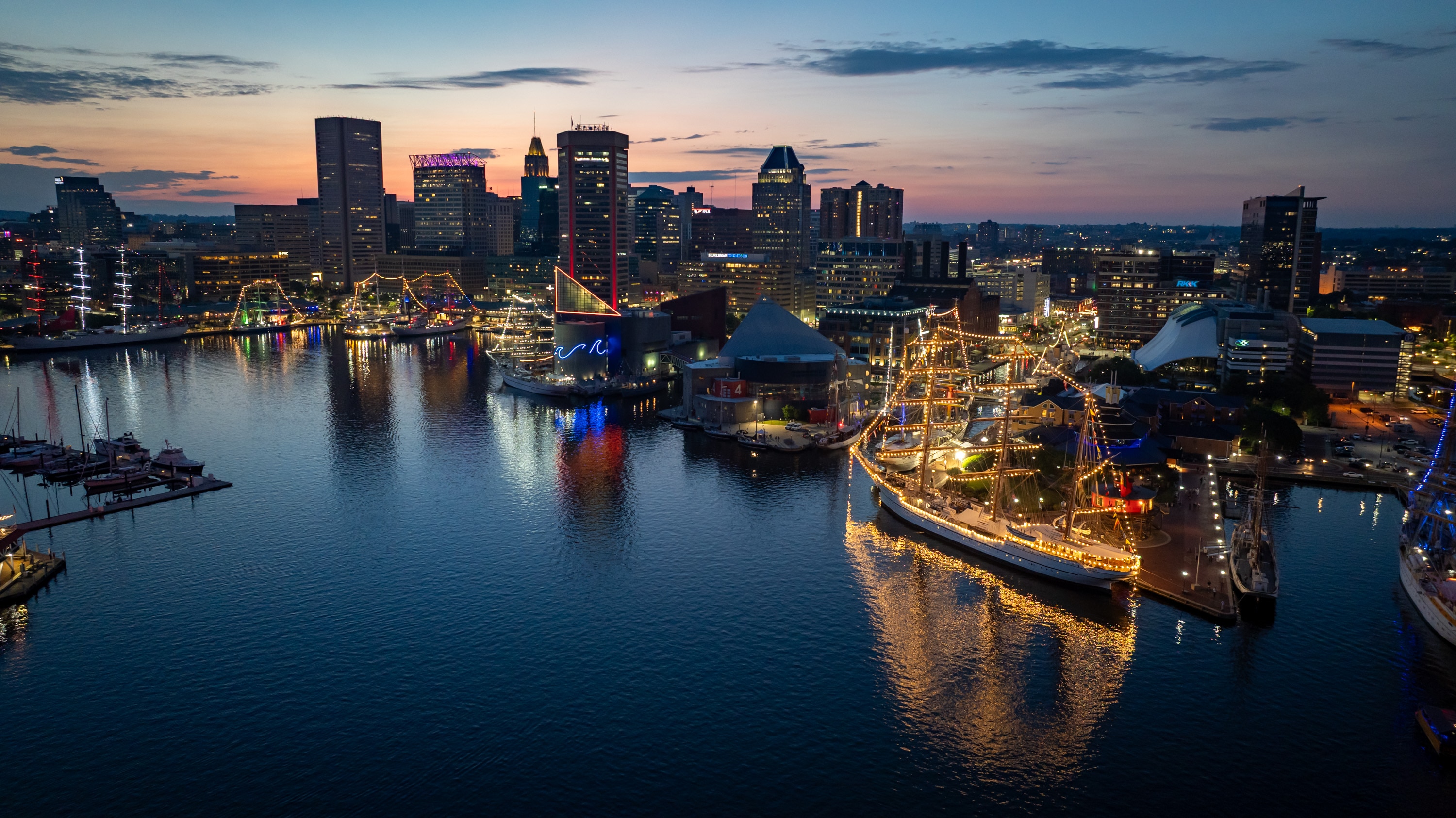 Tall ships visiting for Sail250 light up Baltimore’s Inner Harbor after sunset on Sunday. 
