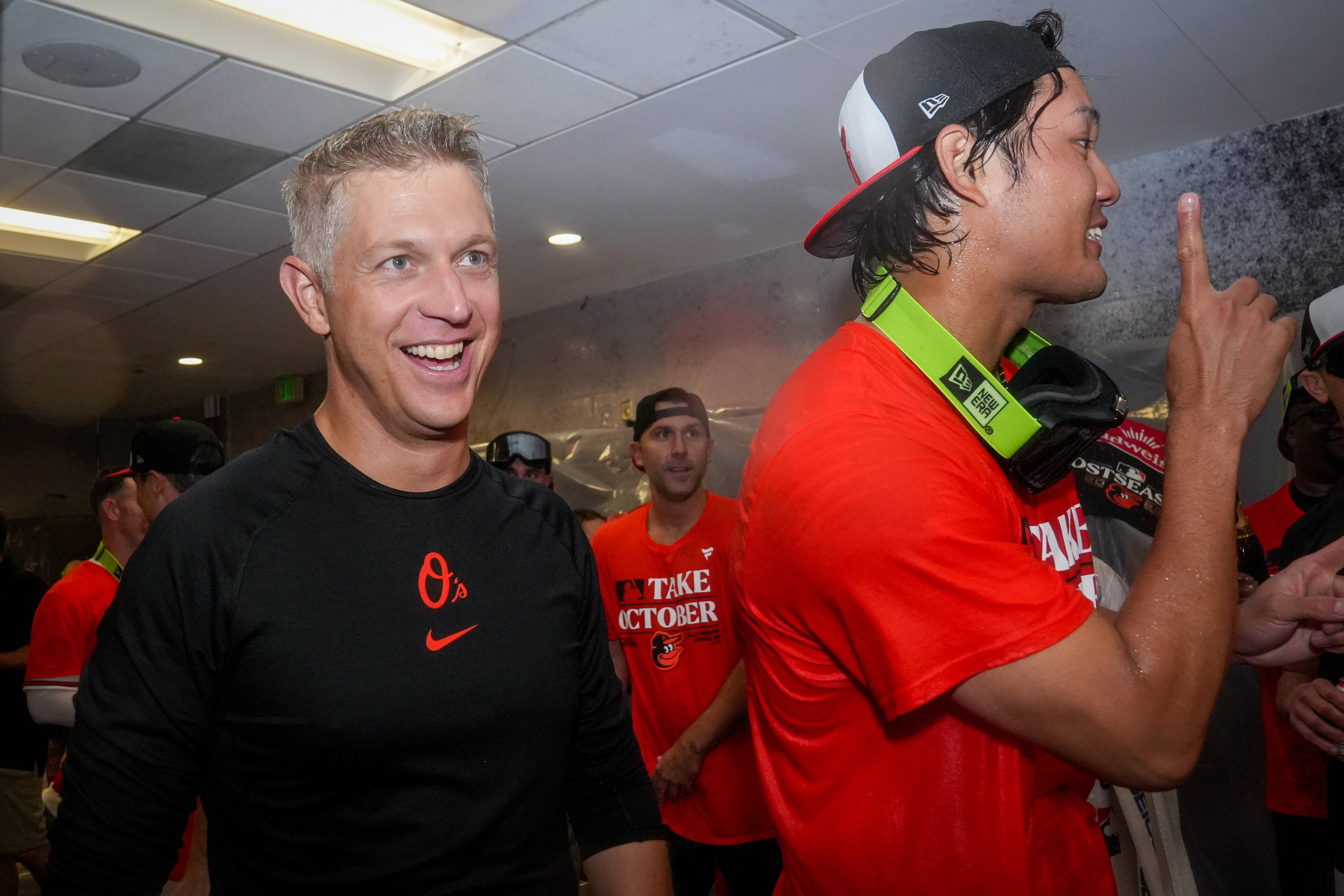 Baltimore Orioles general manager Mike Elias, left, smiles as he walks around the clubhouse following the team’s playoff-clinching win against the Tampa Bay Rays on Sunday, Sept. 17, 2023. The Orioles earned a spot in the playoffs for the first time since 2016.