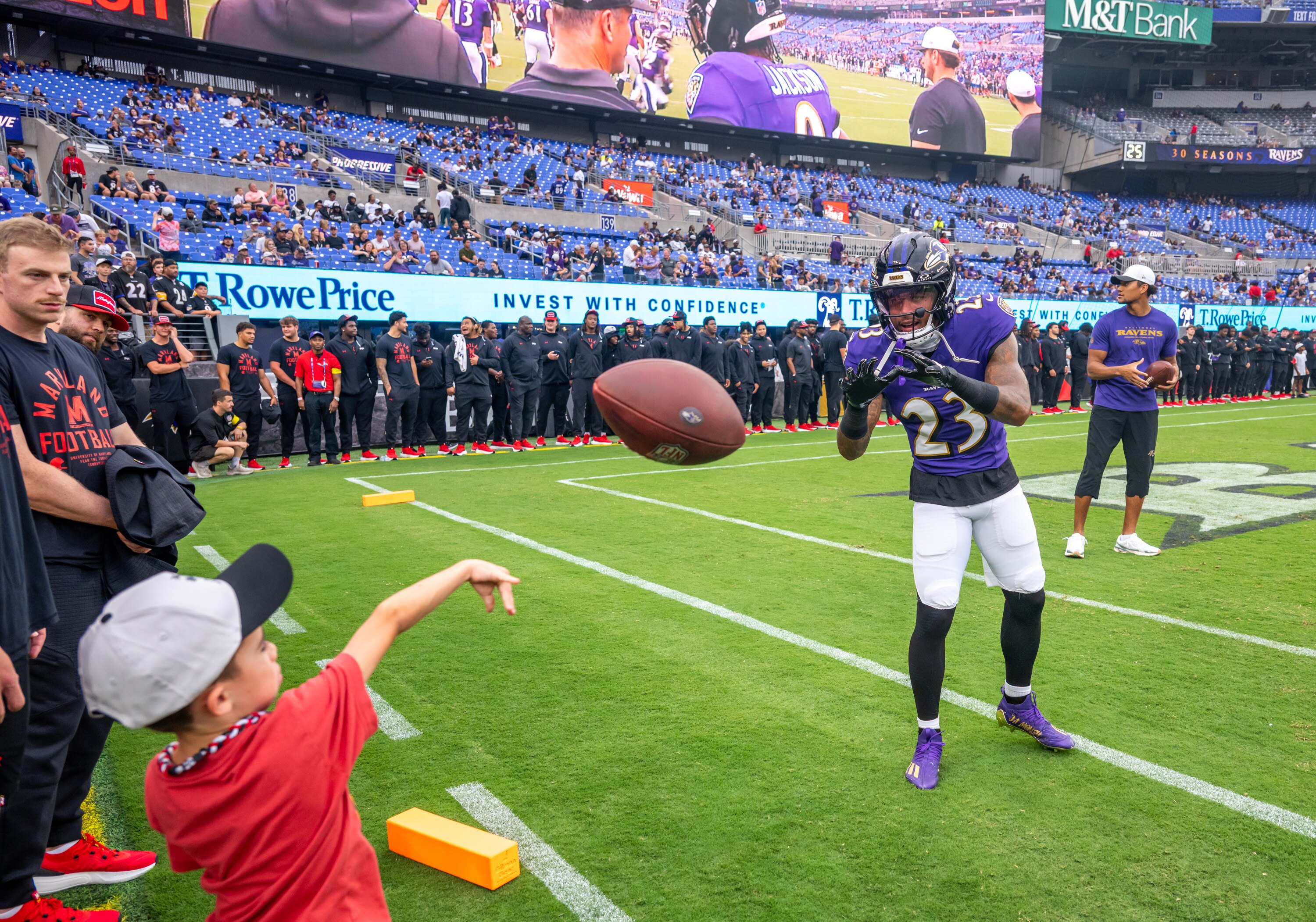 Thursday, Aug. 7, 2025 — Baltimore Ravens cornerback Jaire Alexander (23) plays catch with a fan on the sidelines prior to the Ravens preseason game against the Indianapolis Colts at M&T Bank Stadium.