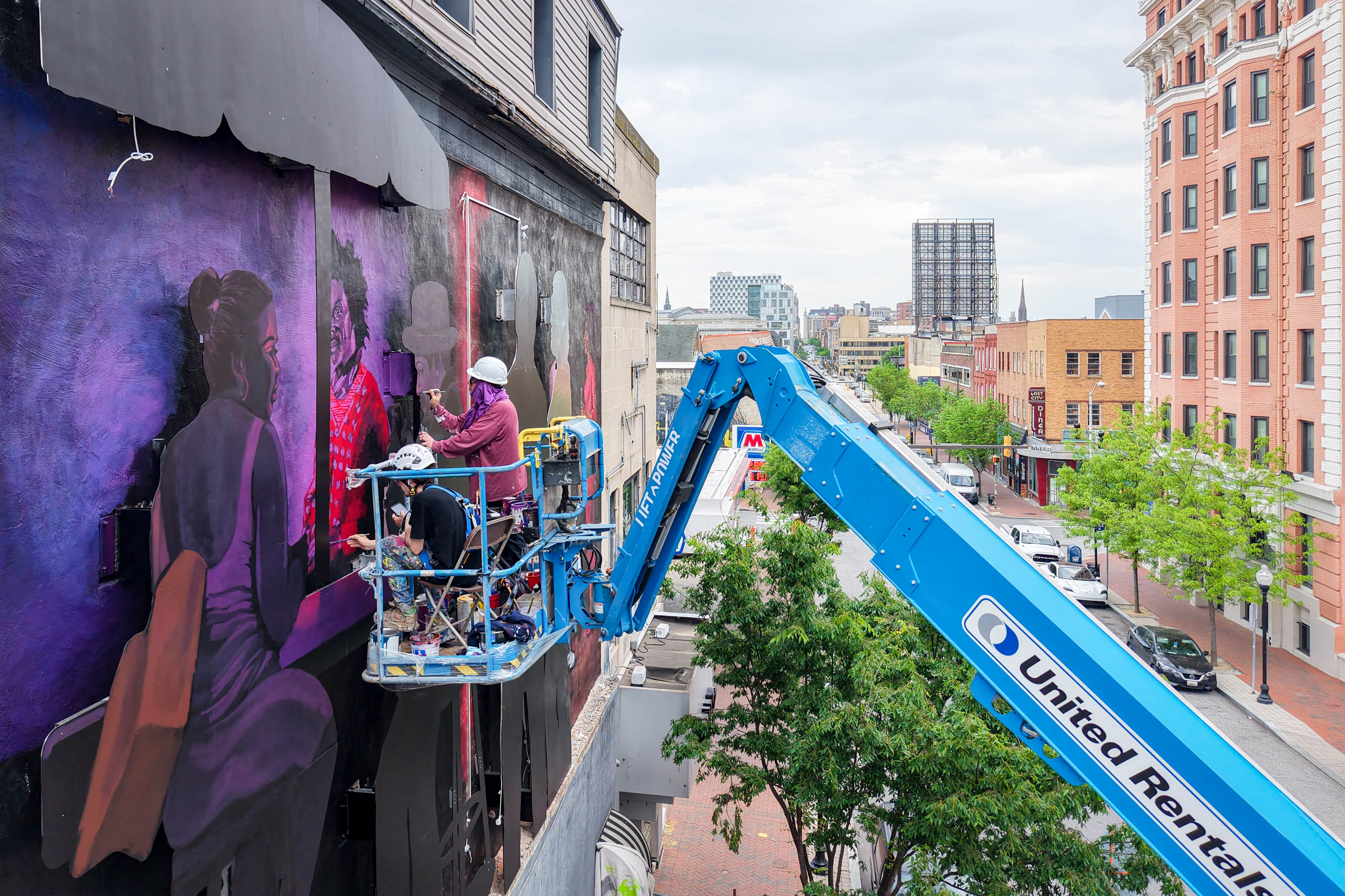 Artist Tony Shore, with assistance from street artist Gaia to his left, works on his installation, "Aurora," outside of the old Gatsby's nightclub in the Station North neighborhood of Baltimore in April.
