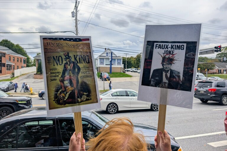 A protester holds up two signs Saturday at the No Kings Rally near Annapolis. About 600 people walked along Generals Highway and Bestgate Road on Oct. 17, 2026.