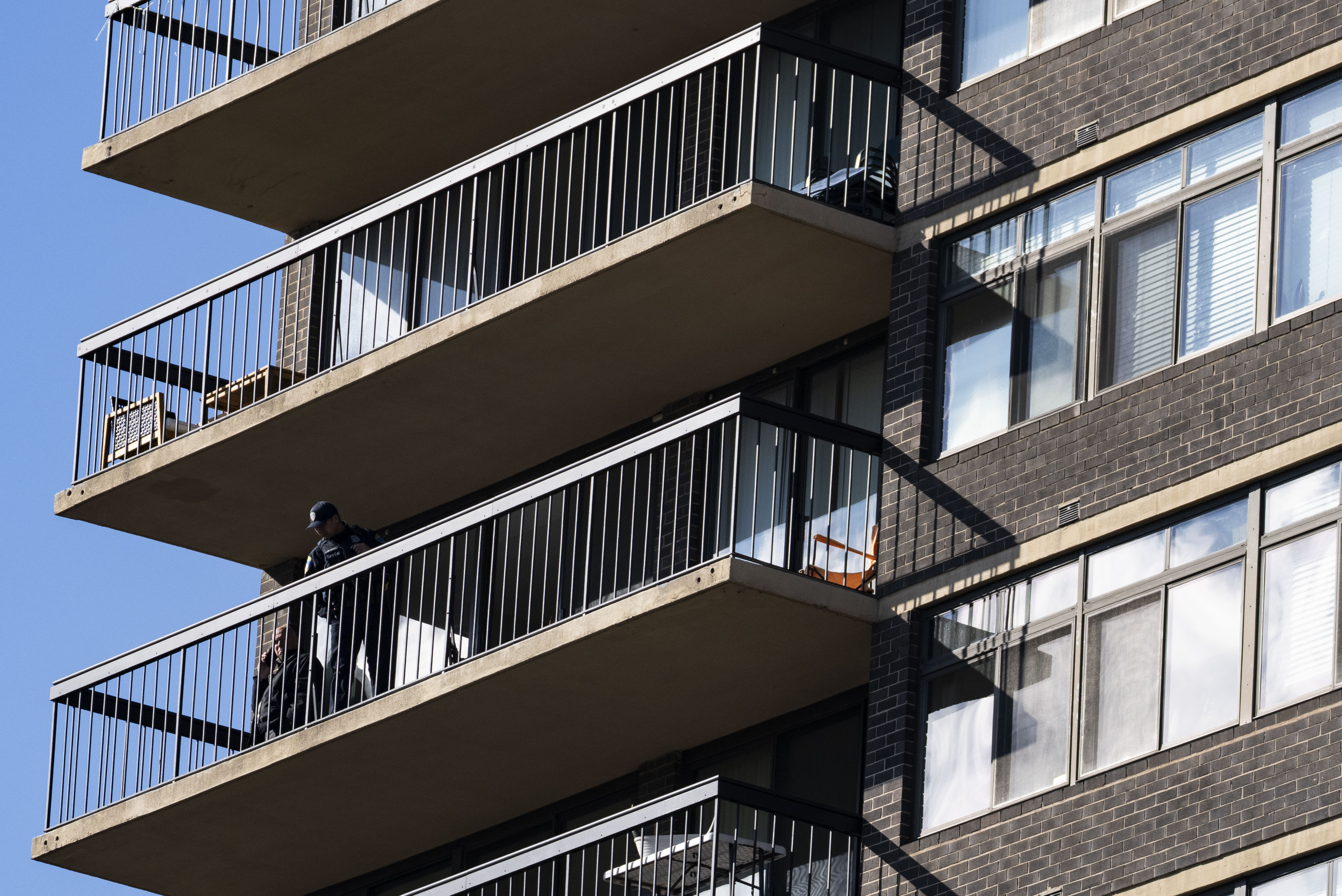 Police stand on the balcony of a ninth floor apartment while investigating after an officer shot a knife-wielding person at 1111 Park Ave. in Baltimore on Monday.