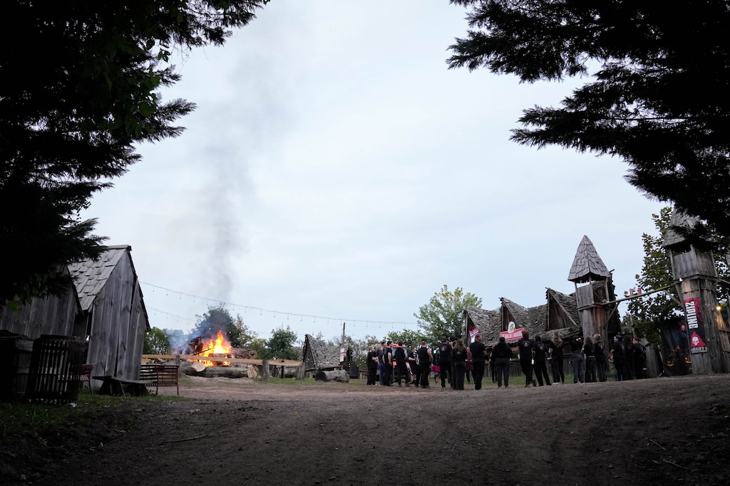 Staff members hold a team meeting near the midway bonfire before doors open at Markoff's Haunted Forest in Dickerson, Md. on Friday, October 9, 2026.