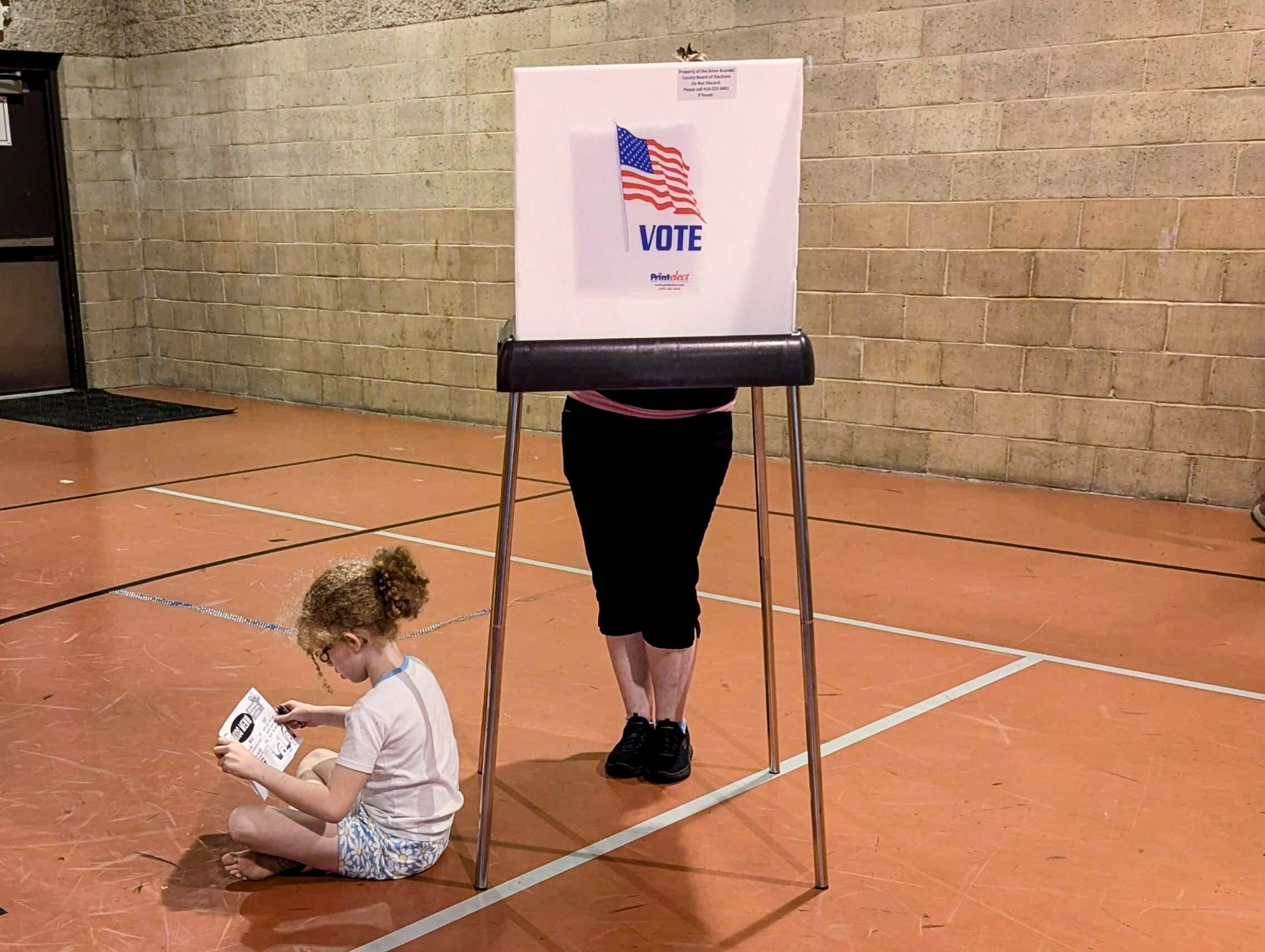 Tennley Cook waits on the floor of the Eastport Community Center gym while her mother Heather Cook votes Tuesday night in Annapolis.
