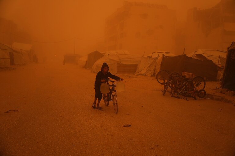 A boy pushes a bicycle carrying jerrycans of water through a sandstorm in Khan Younis, southern Gaza Strip, Saturday, March 14, 2026.