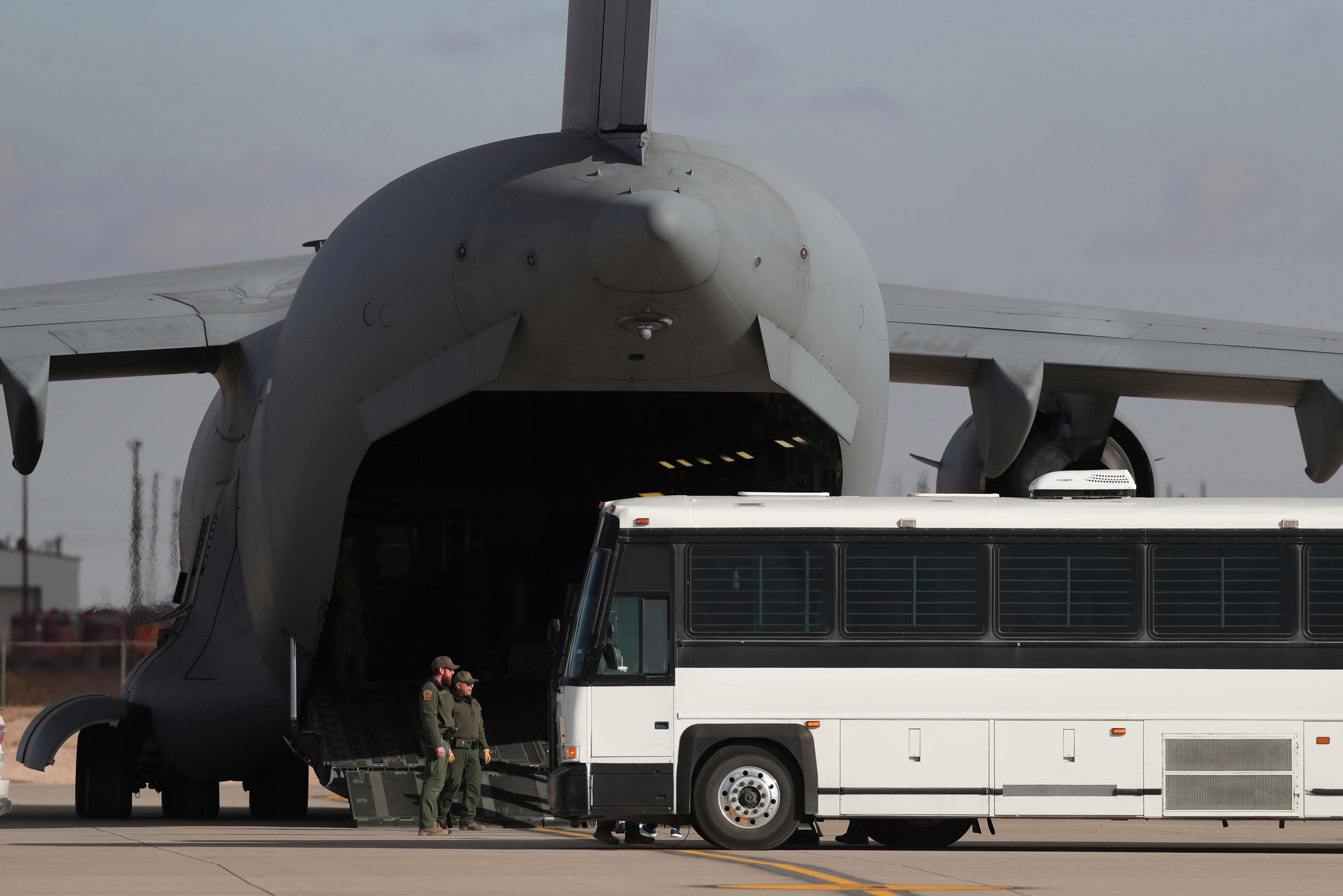 FILE - A military aircraft waits for migrants to board from a bus at Fort Bliss in El Paso, Tx., Thursday, Jan. 30, 2025, before deporting them to Guatemala.