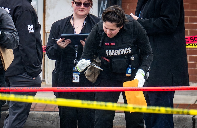 A forensics technician picks up a knife at the scene of a police-involved shooting on the 1700 block of Pennsylvania Avenue on Thursday.