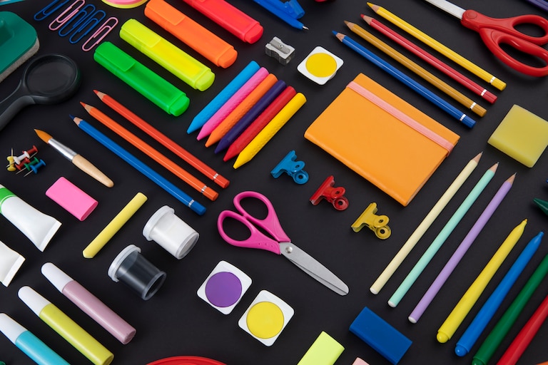 An assortment of colorful school supplies laid out on a black background