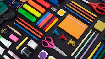 An assortment of colorful school supplies laid out on a black background
