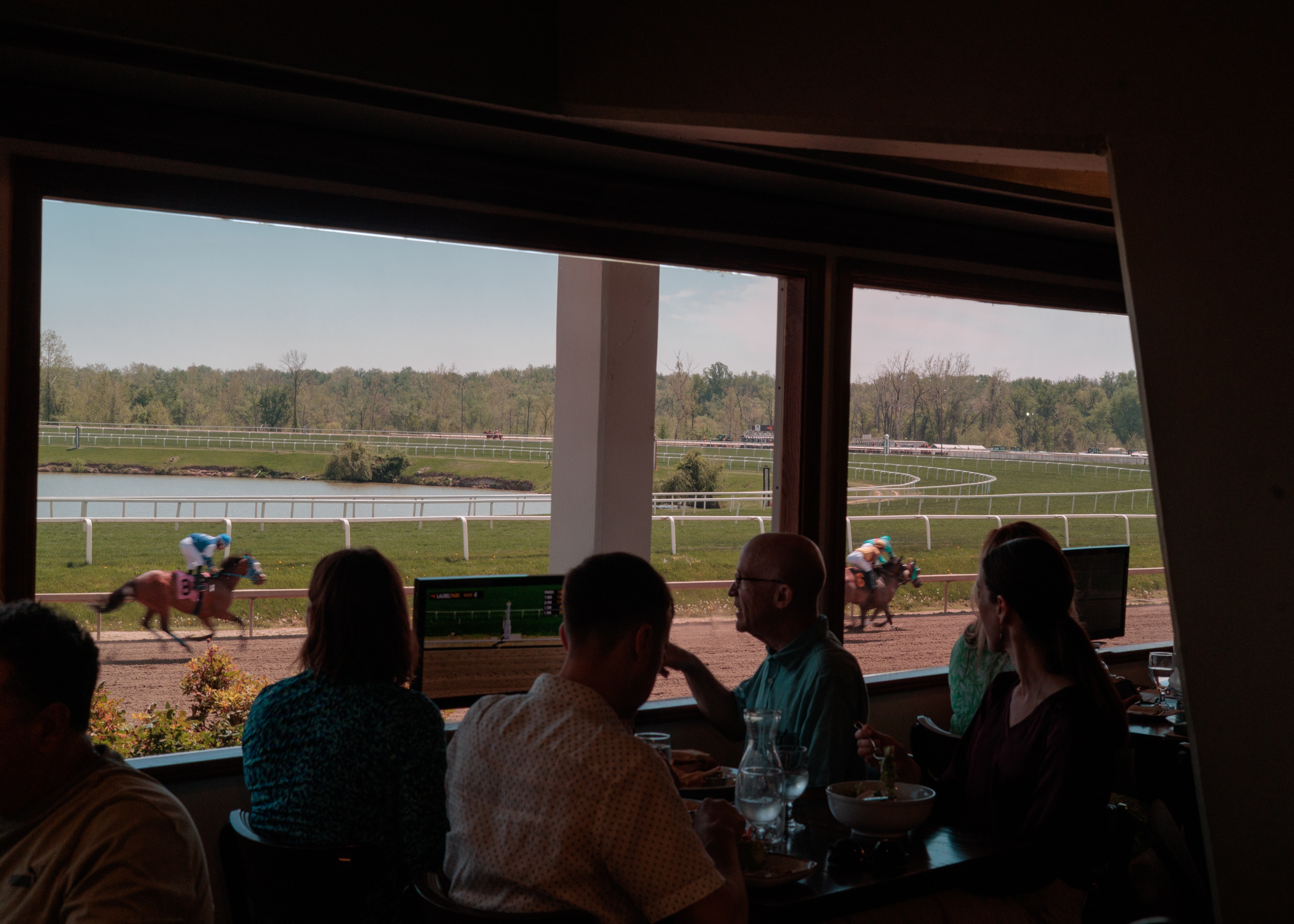 Guests dine at Tips Restaurant as horses run by during a race at Laurel Park.