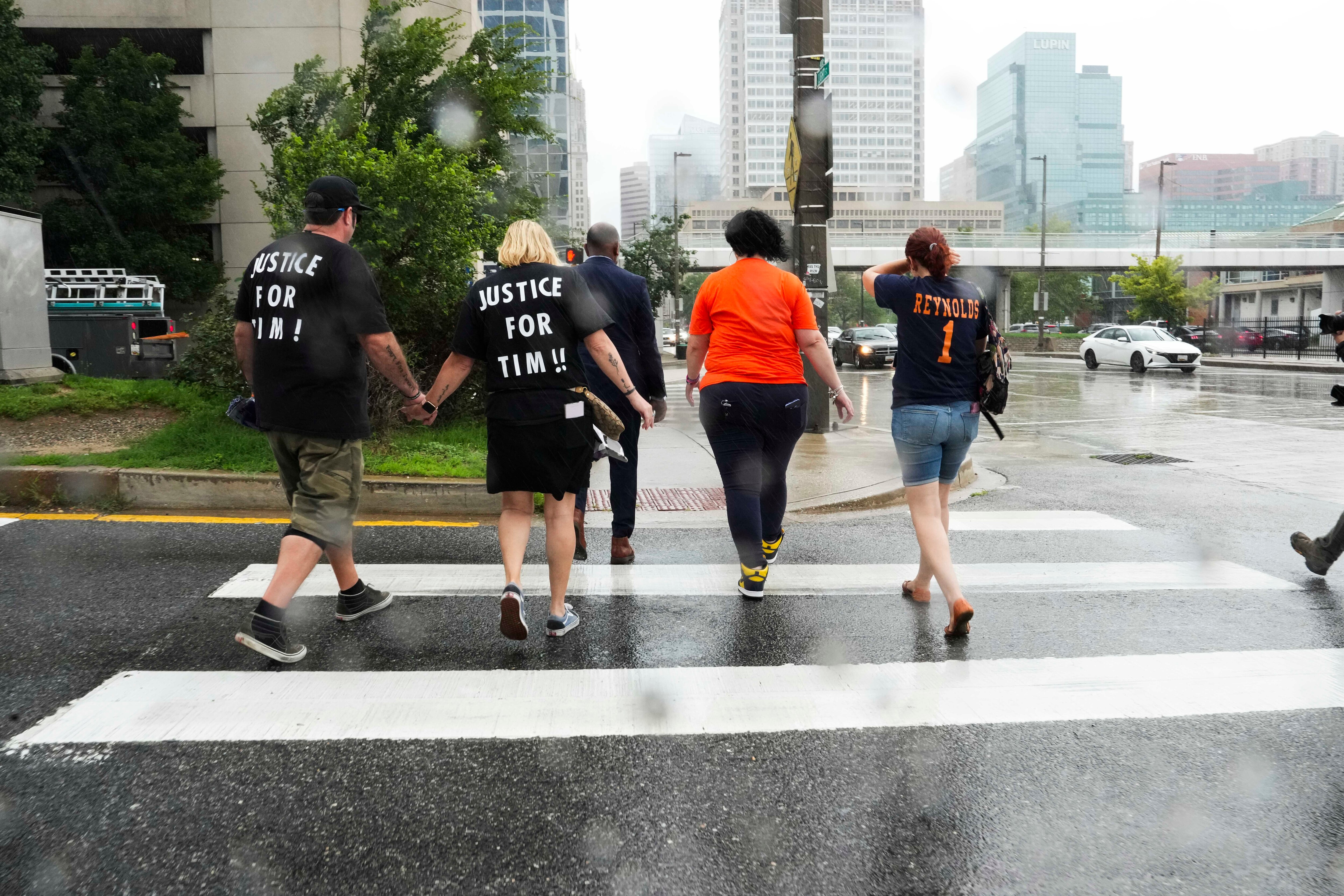 Family members and friends of Timothy Reynolds, 48, of Hampden, visit the intersection of Light and Conway streets near the Inner Harbor in Baltimore on the anniversary of his death. Reynolds was shot and killed after confronting a group of squeegee workers with a baseball bat on July 7, 2022. A 16-year-old is standing trial in Baltimore Circuit Court on charges including first-degree murder.