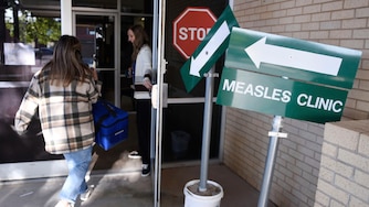 FILE - Health department staff members enter the Andrews County Health Department measles clinic carrying doses of the measles, mumps and rubella vaccine, April 8, 2025, in Andrews, Texas. (AP Photo/Annie Rice, File)