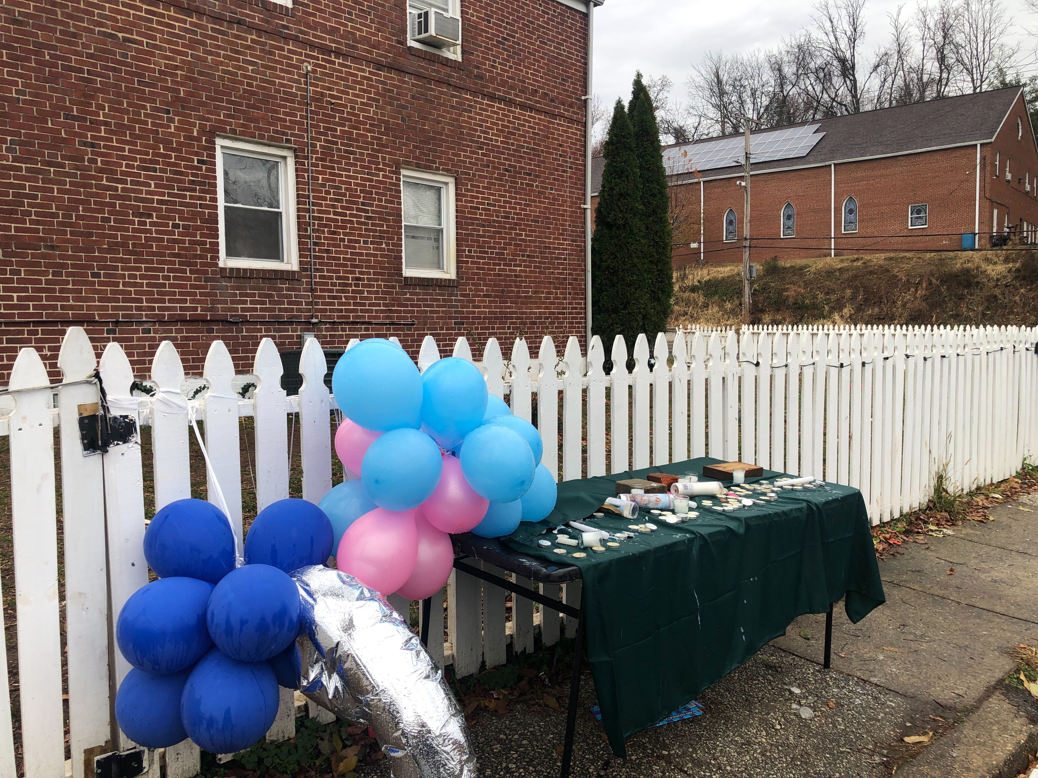 A folding table on the sidewalk was covered in a green tablecloth, with spent candles and trails of wax.