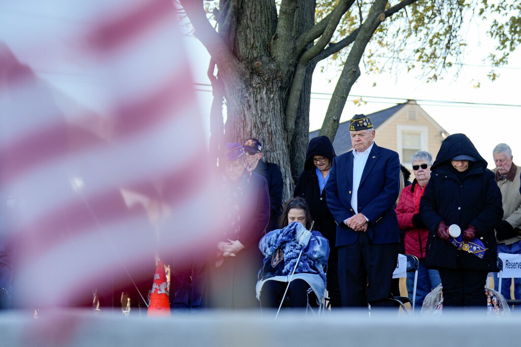 Attendees bow their heads in prayer at Veterans Memorial Park, just outside of Wells-McComas VFW Post 2678, during a Veterans Day observance ceremony in Sparrows Point, Md., on Tuesday, November 11, 2025.