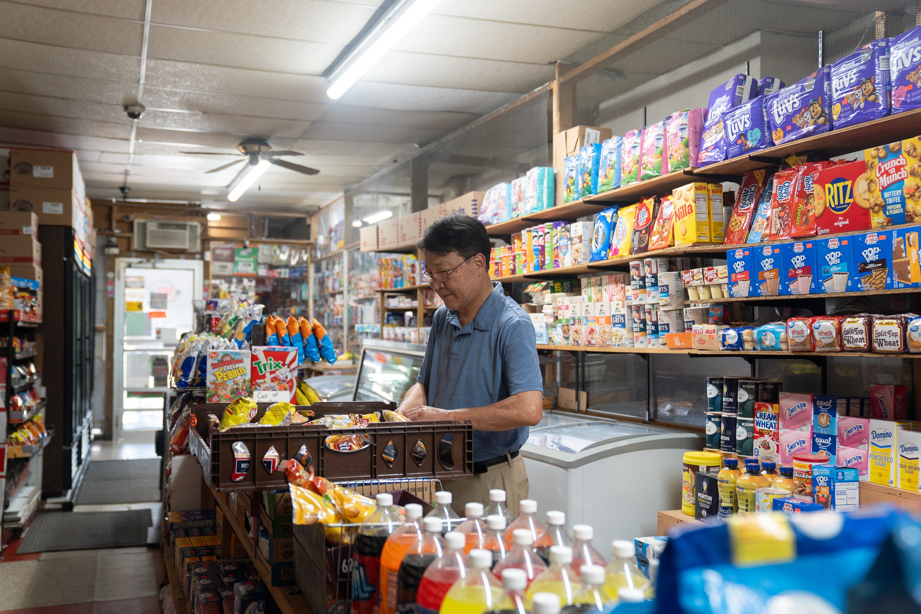 Kevin Lee stocks an aisle at Lee’s Mini Market, a corner store he and his wife own and run in West Baltimore.